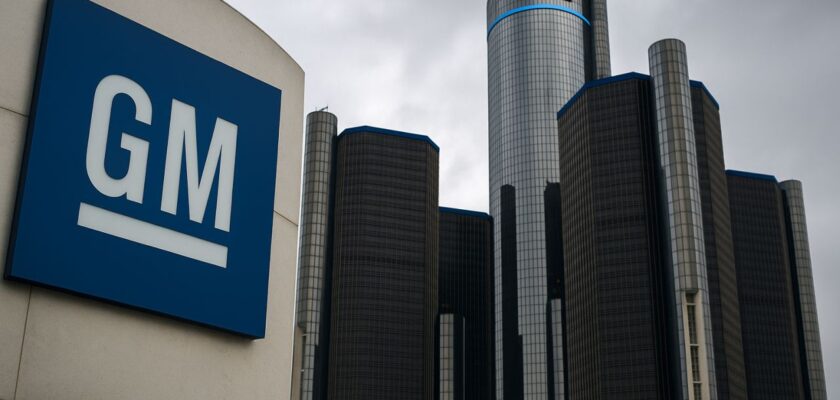 insegna General Motors in primo piano con dei grattacieli dietro