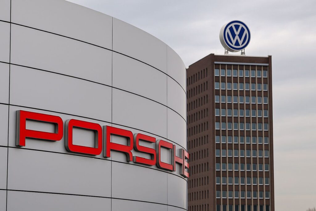 Un edificio con la scritta Porsche in primo piano e uno sullo sfondo con il simbolo Volkswagen in cima