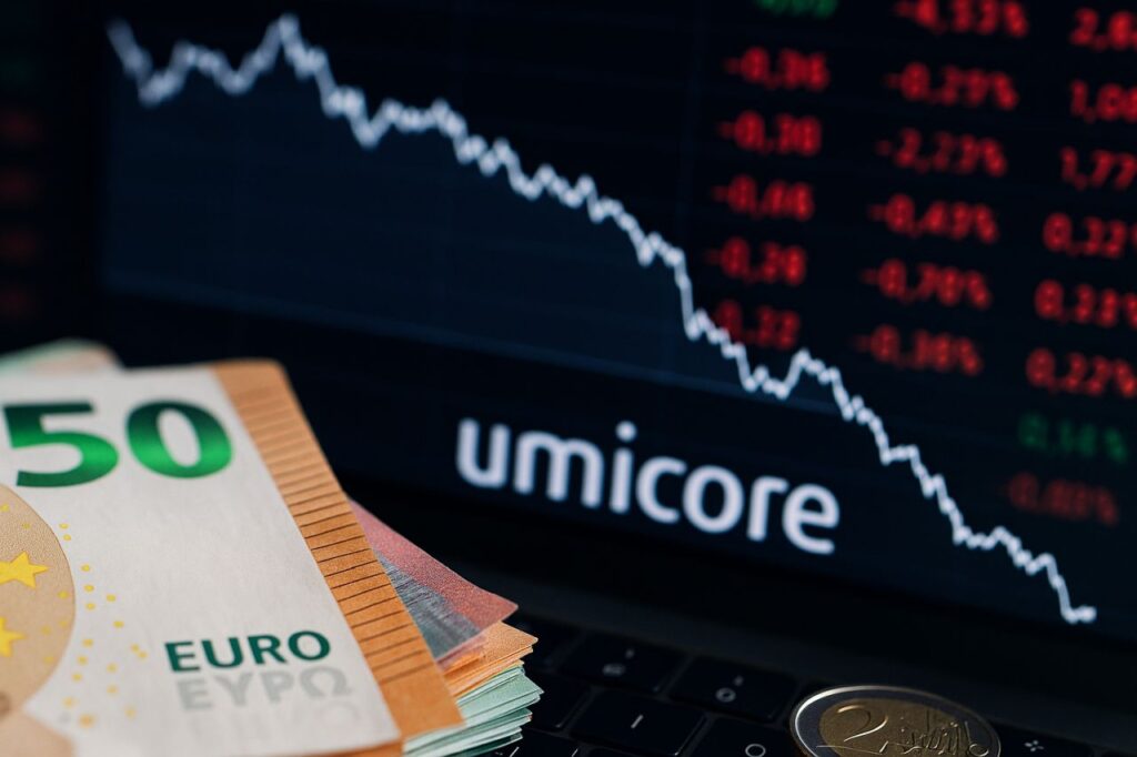 Alcune banconote in euro con la scritta Umicore sullo sfondo insieme a un grafico finanziario