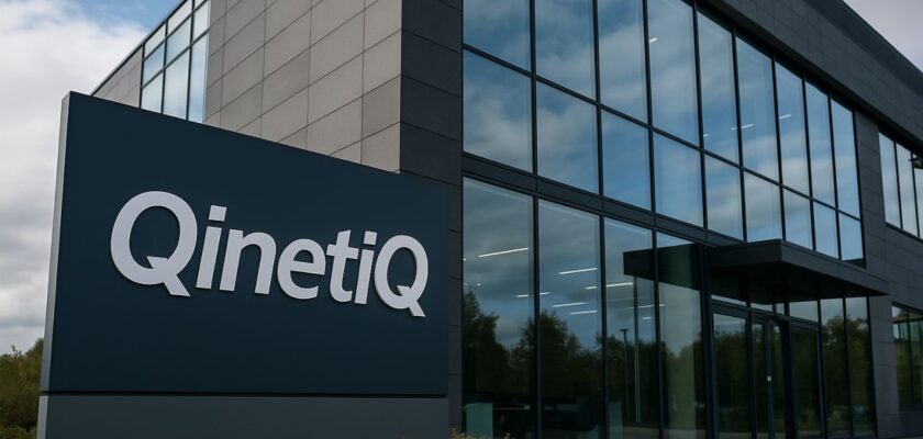 Un totem pubblicitario con la scritta QinetiQ e un edificio con una grande vetrata sullo sfondo