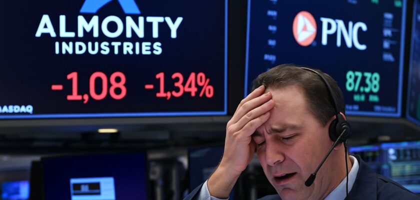 Un investitore con la mano sulla fronte in una sala di Borsa. Sullo sfondo logo e scritta Almonty