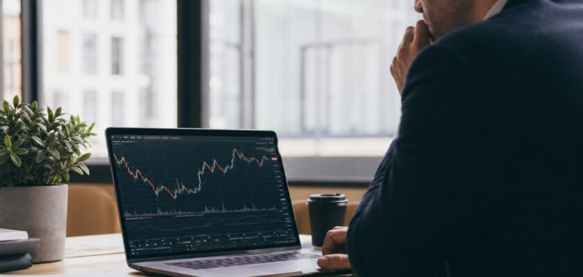 Professionista al desk osserva grafici finanziari sul laptop in un ufficio