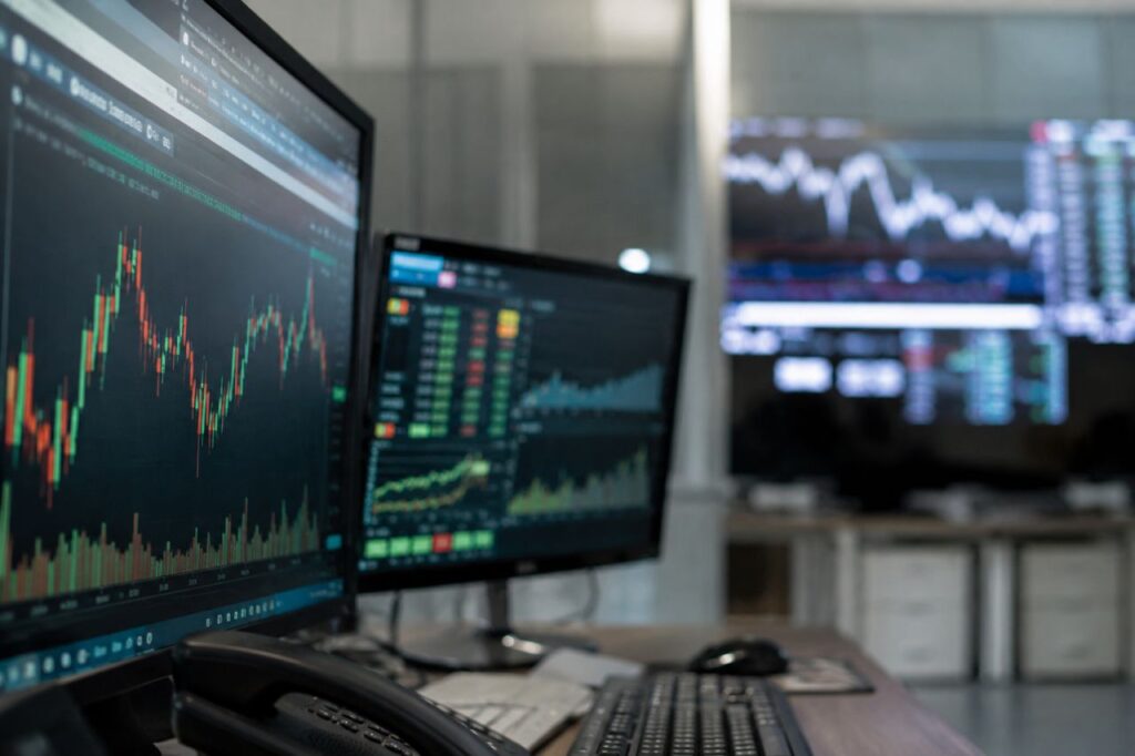 Monitor finanziari in ufficio con grafici di Borsa su schermo