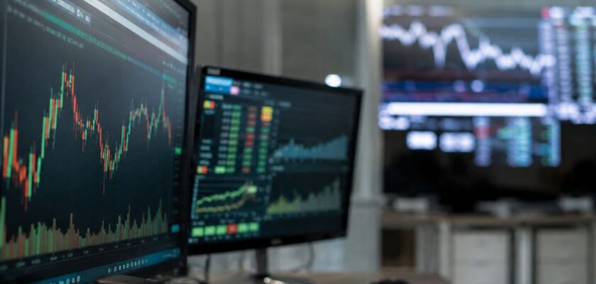 Monitor finanziari in ufficio con grafici di Borsa su schermo