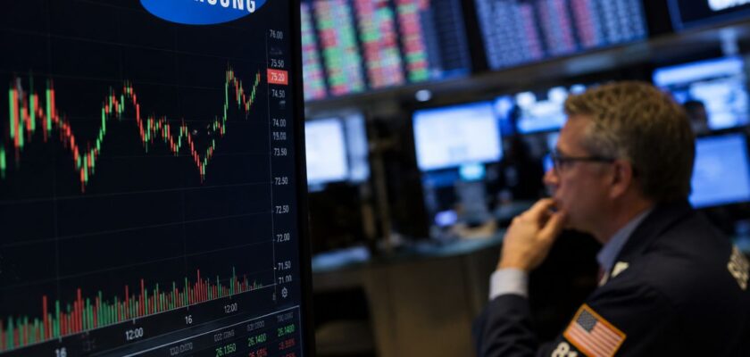 Sala produttiva di semiconduttori Samsung con trader screen finanziari sullo sfondo