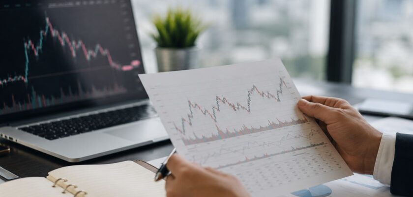 Analisi finanziaria in ufficio moderno, con grafici di mercato e documenti di investimento su una scrivania professionale