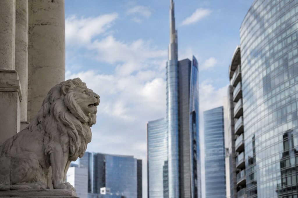 Statua di leone in pietra in primo piano davanti a moderni grattacieli di vetro nel centro finanziario di una grande citt&agrave;