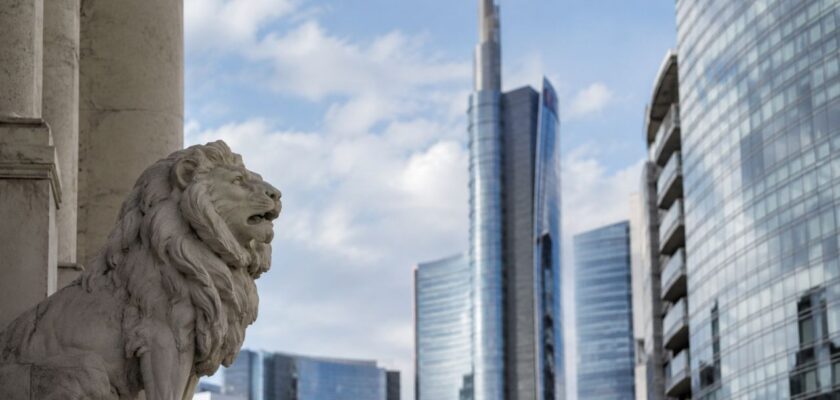 Statua di leone in pietra in primo piano davanti a moderni grattacieli di vetro nel centro finanziario di una grande città