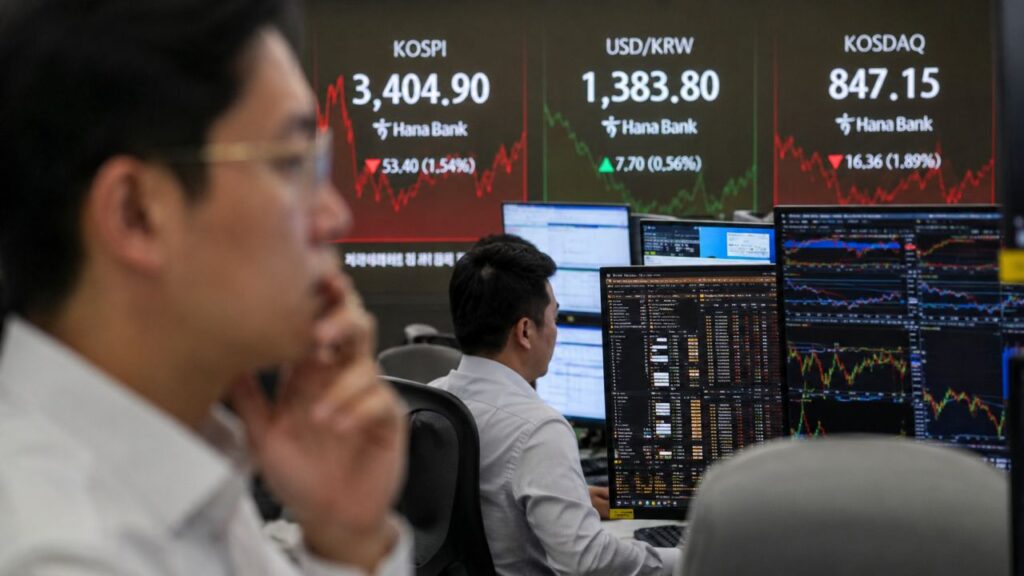 Trader davanti a monitor finanziari con grafici di mercato e quotazioni del KOSPI