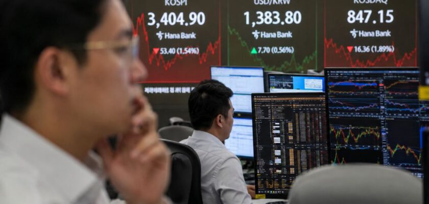 Trader davanti a monitor finanziari con grafici di mercato e quotazioni del KOSPI