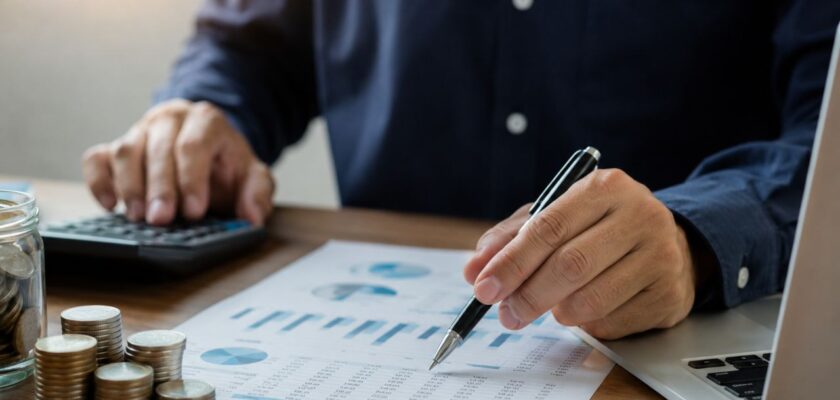 Persona seduta a un tavolo mentre pianifica il proprio futuro finanziario, con documenti, grafici e strumenti legati a risparmio, investimenti e previdenza integrativa