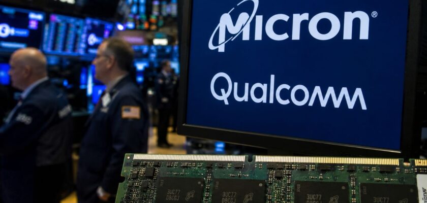 Schermo con i loghi Micron e Qualcomm davanti a un chip di memoria, sullo sfondo la sala operativa di una borsa valori con trader e monitor finanziari