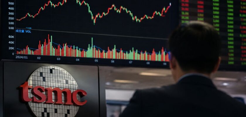 Uomo in giacca osserva un grande monitor con grafici di Borsa; in primo piano è visibile il logo TSMC, richiamo al settore dei semiconduttori e degli investimenti finanziari