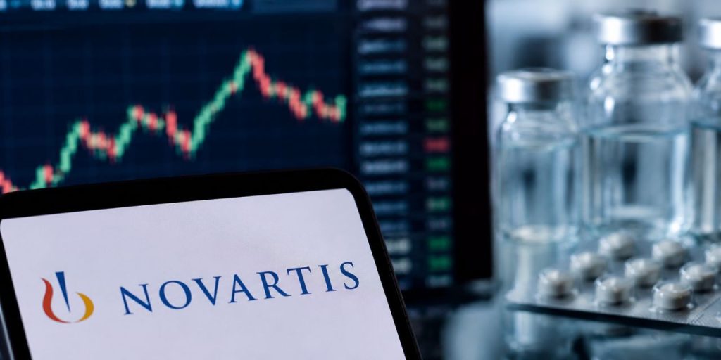 Logo Novartis in primo piano, grafico di Borsa sullo sfondo e flaconi di farmaci con compresse