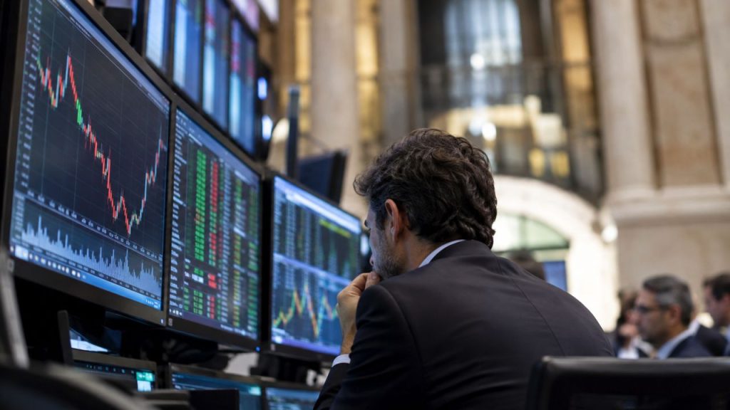 Operatore finanziario osserva monitor con grafici e quotazioni di Borsa, all’interno di una sala trading